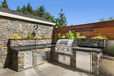 An L shaped outdoor kitchen with stone veneer