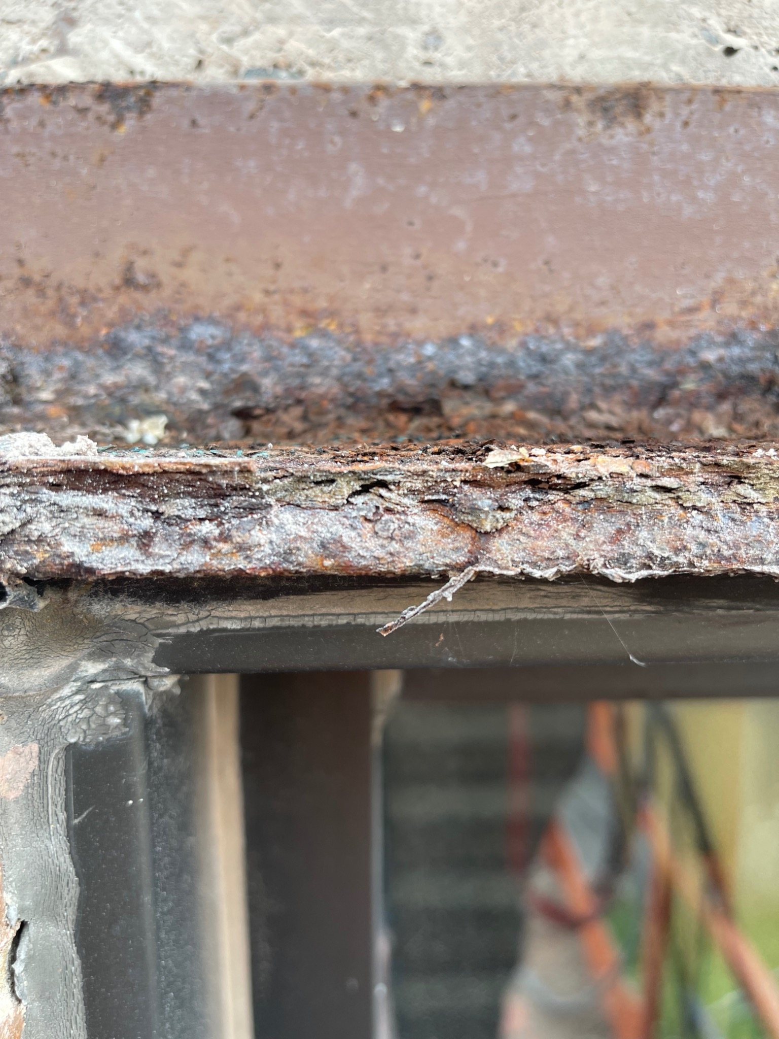 Layered rust expansion on an existing steel lintel beneath brick masonry