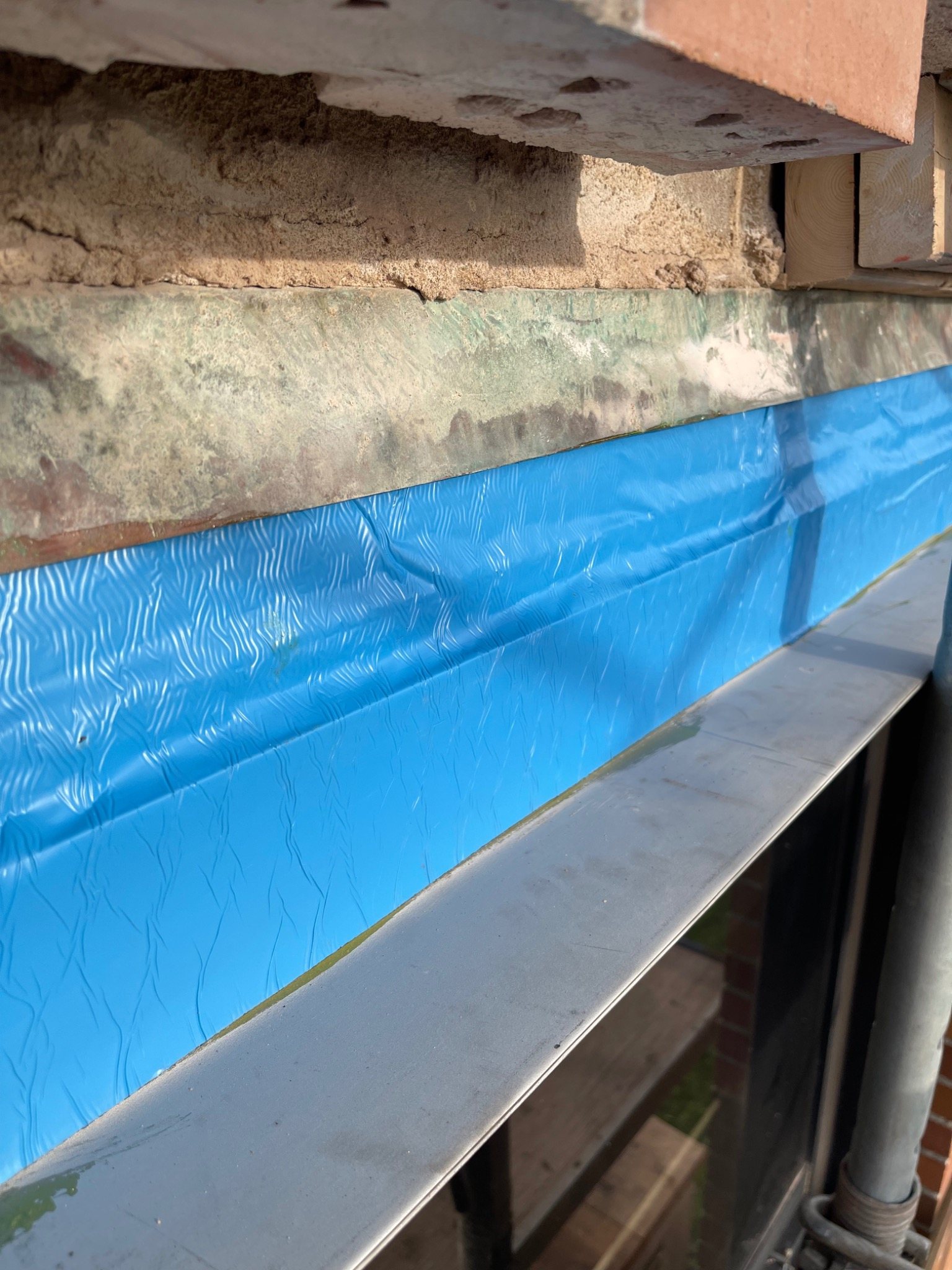 New stainless steel lintel with primed BlueSkin membrane beneath existing through-wall copper flashing