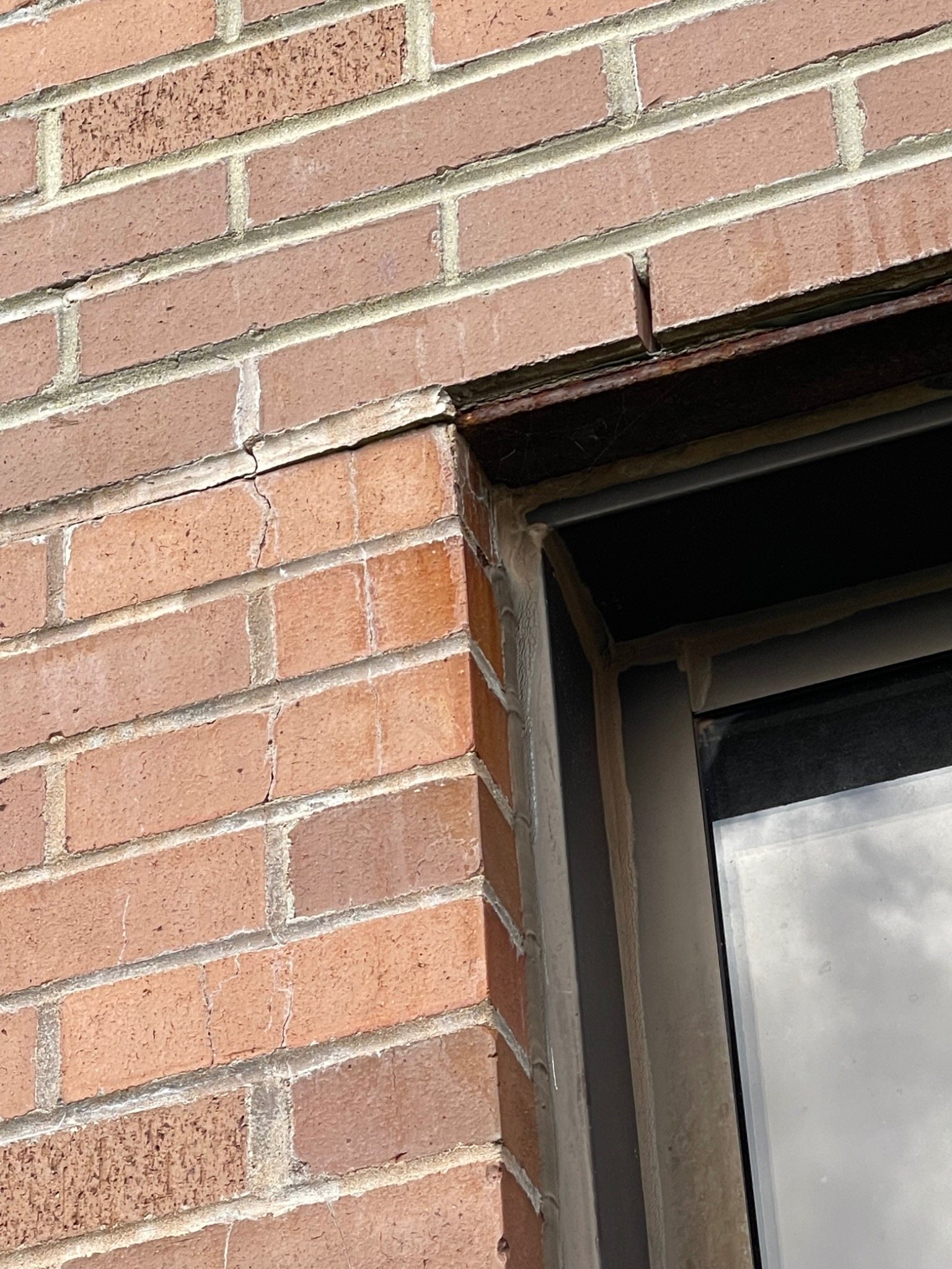Cracked brickwork and exposed lintel area beside a window during armoury masonry repair