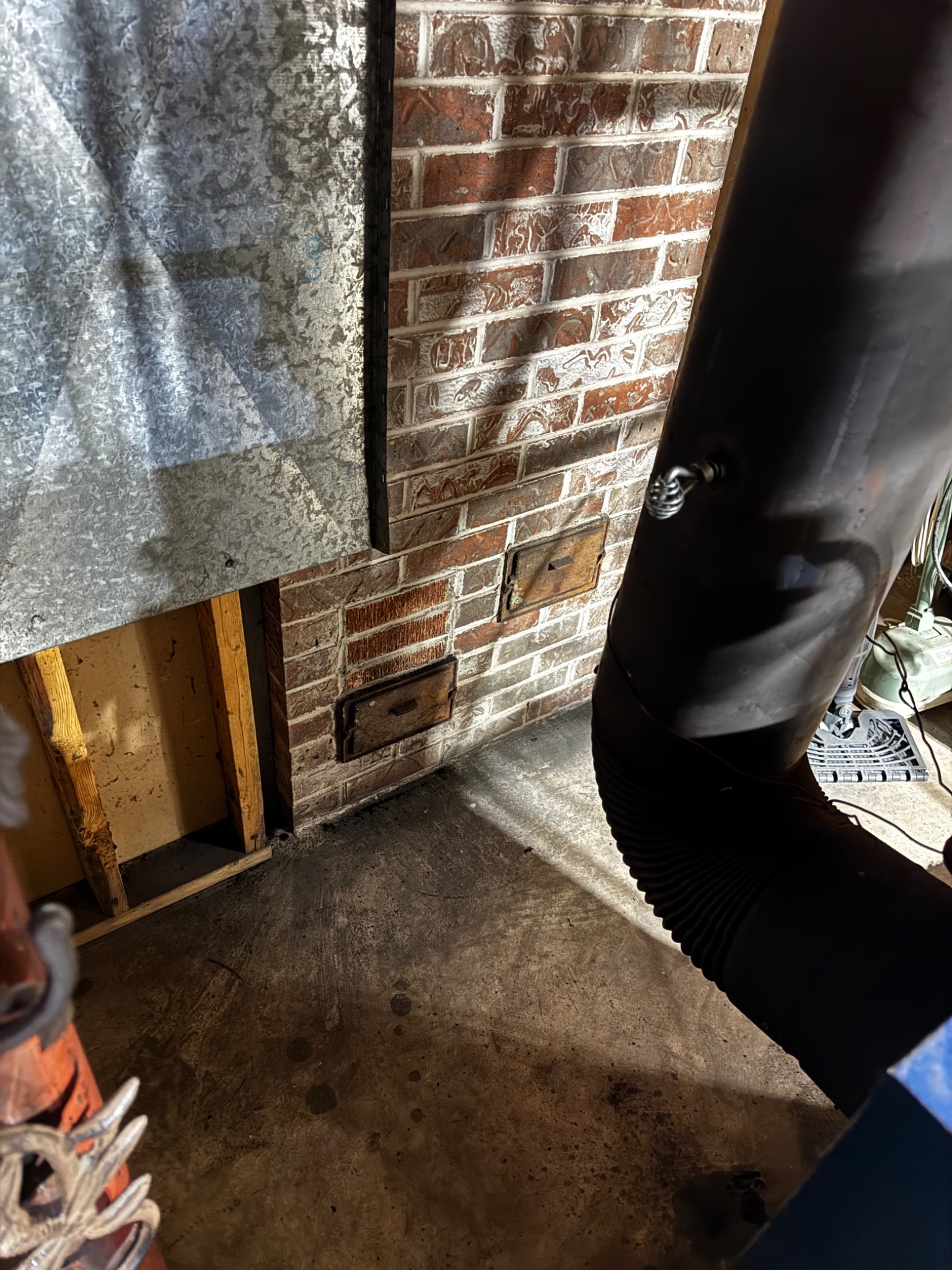 Chimney cleanout and masonry chimney at basement level after a lightning strike