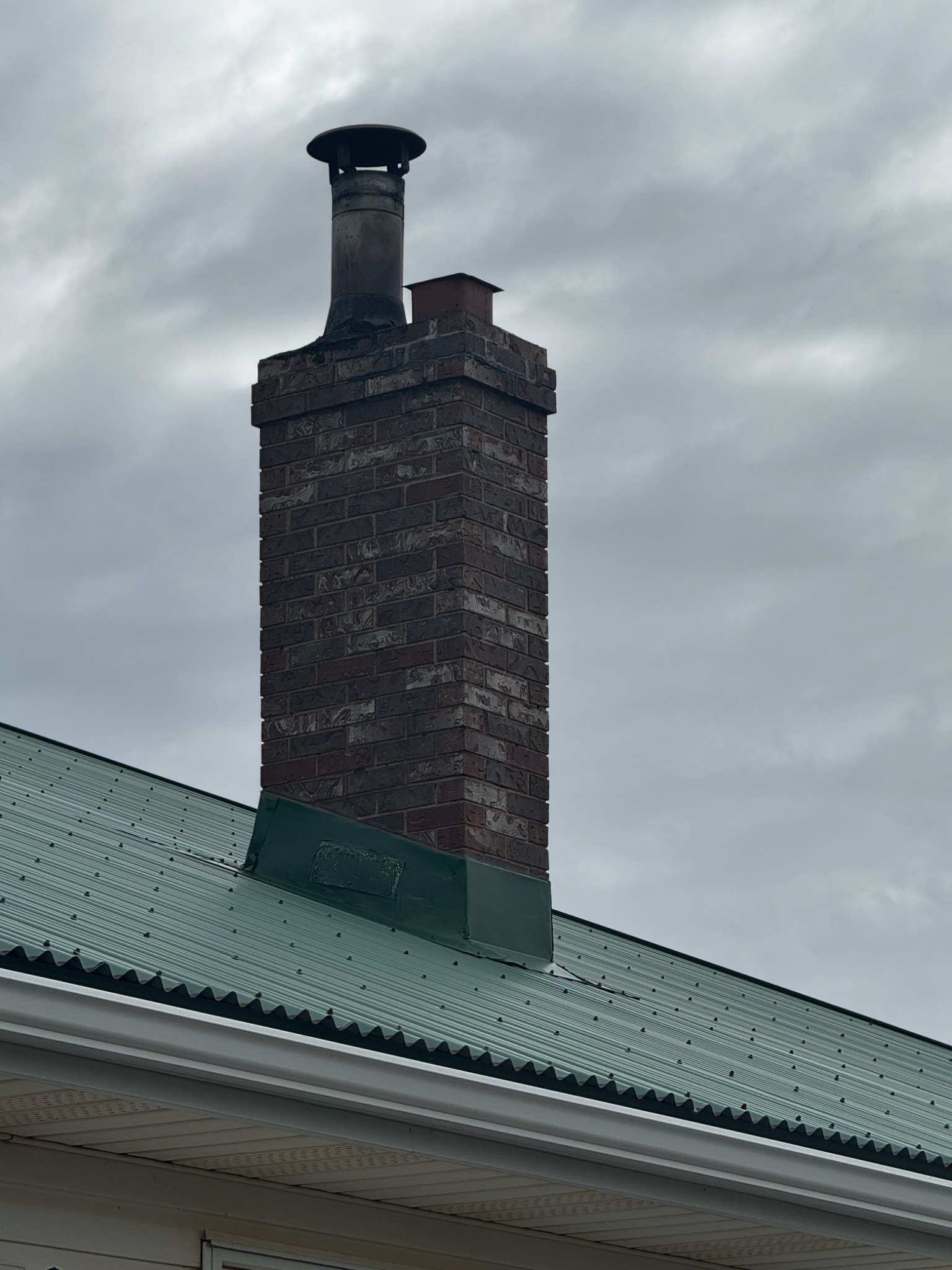 Repaired area of metal flashing around a masonry chimney after a lightning strike