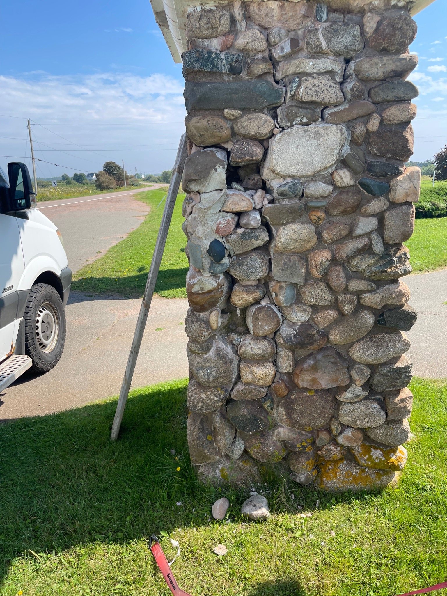 Damaged corner of a Mont-Carmel fieldstone monument showing loosened original stones and internal voids