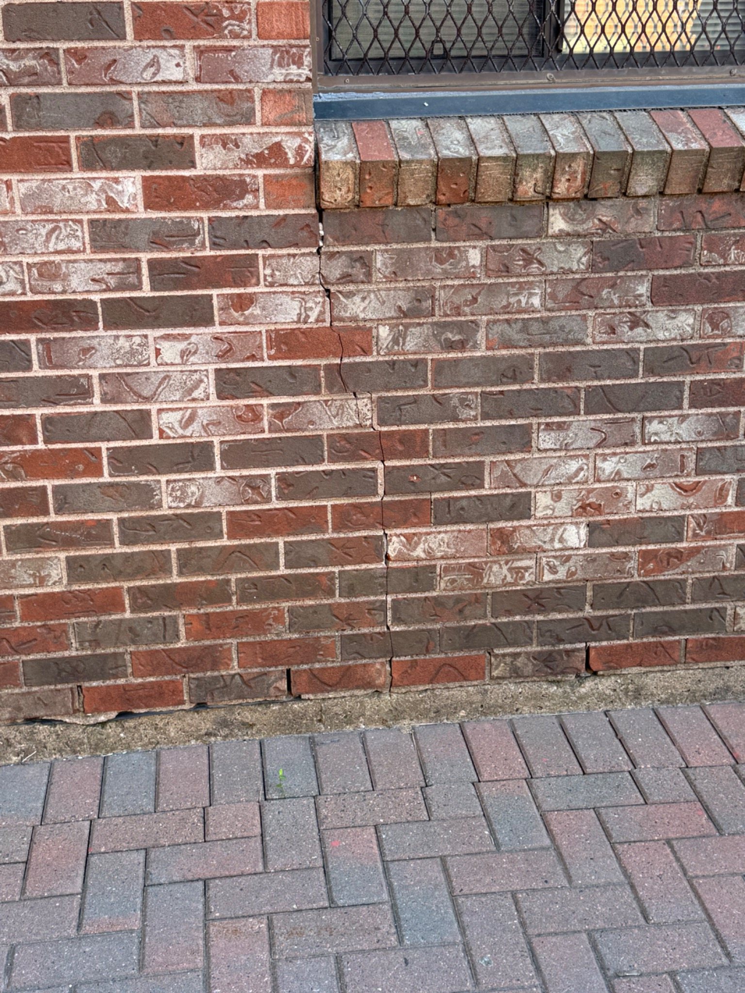 Brick wall with a vertical crack beside an opening