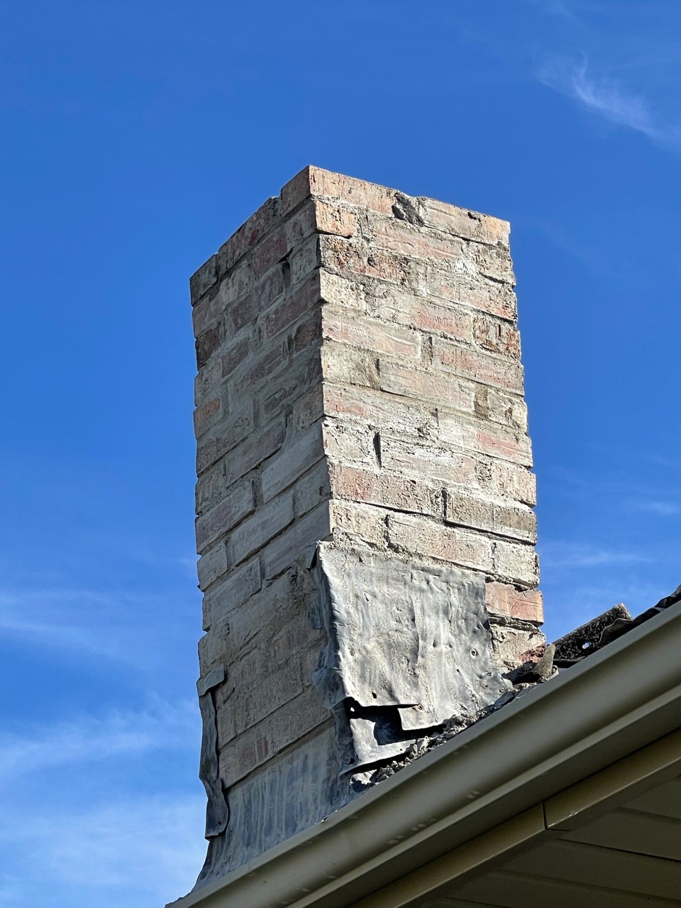 Severely deteriorated chimney with failed brickwork, mortar joints and roofline details in PEI