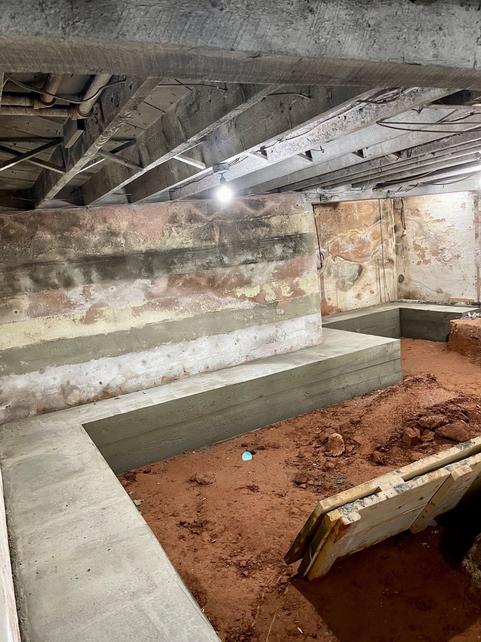 Concrete bench footing built inside a basement to permit a lower floor elevation