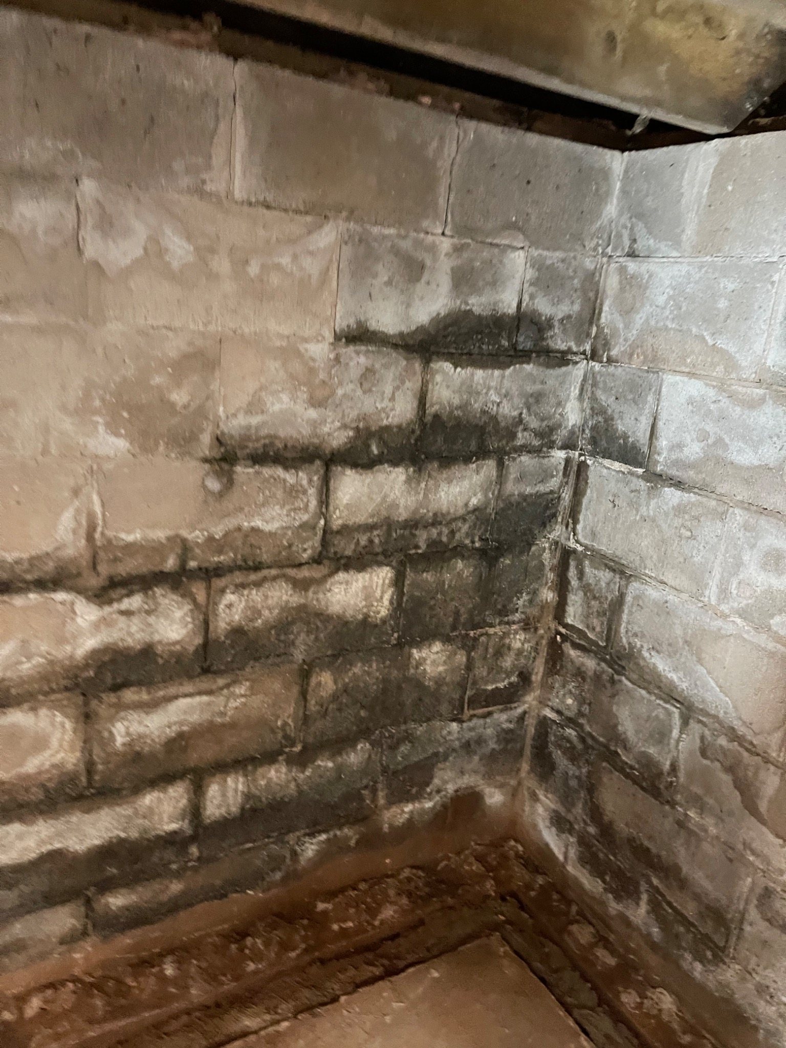 Interior concrete block foundation wall with visible moisture staining