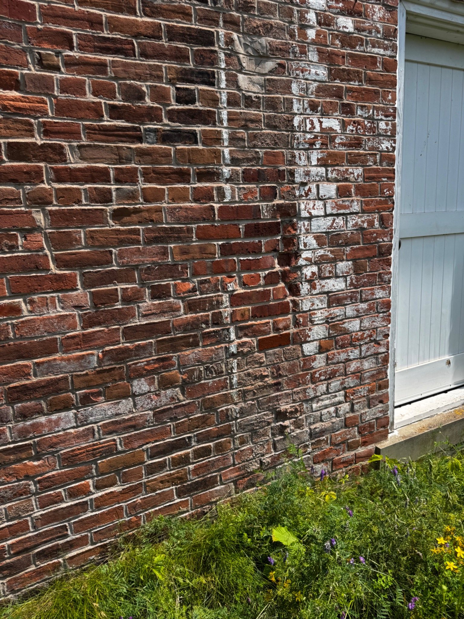 Older brick masonry with pale deposits, mixed repairs and weathered mortar