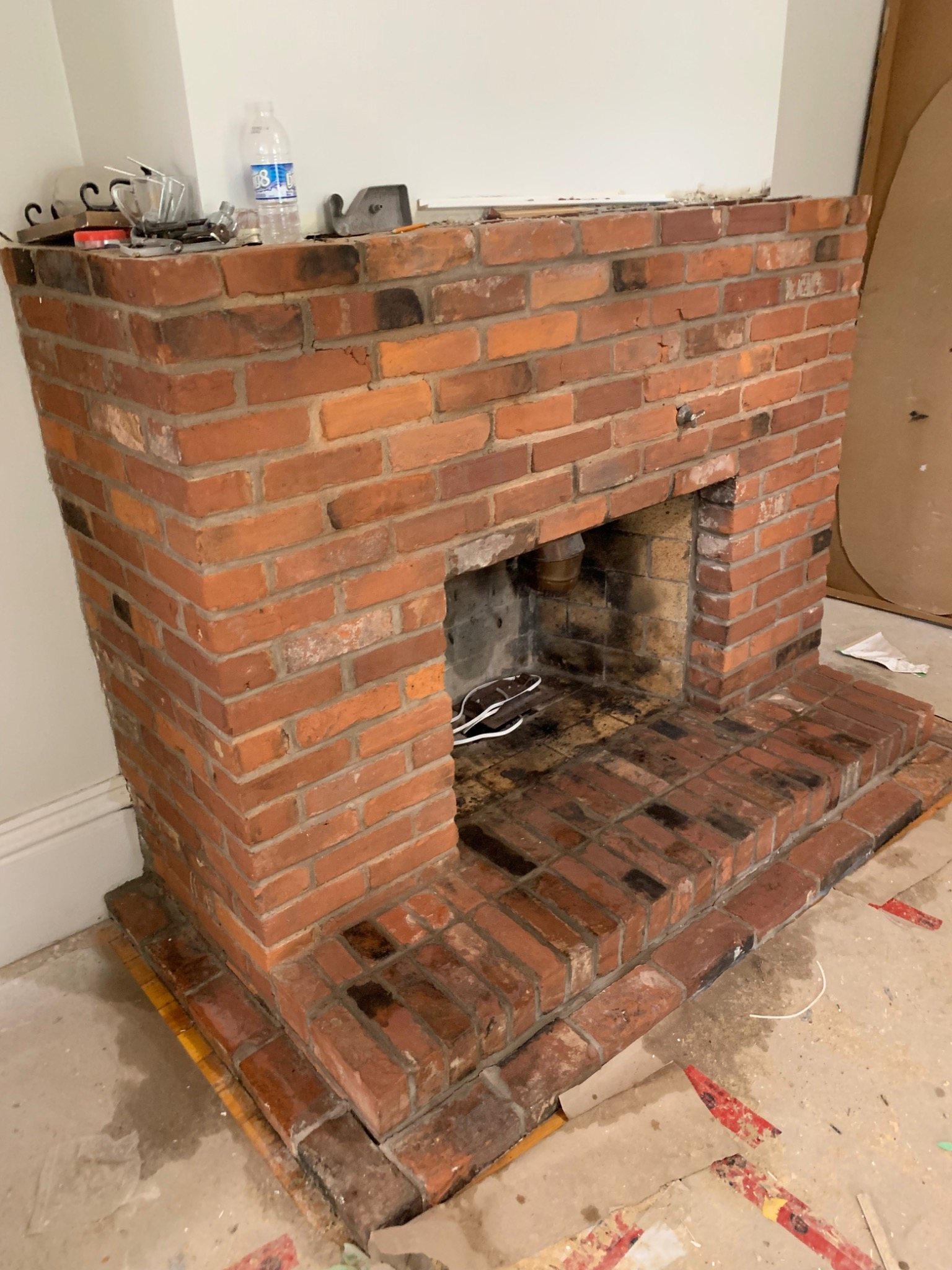 Brick masonry fireplace under renovation with exposed firebox and hearth