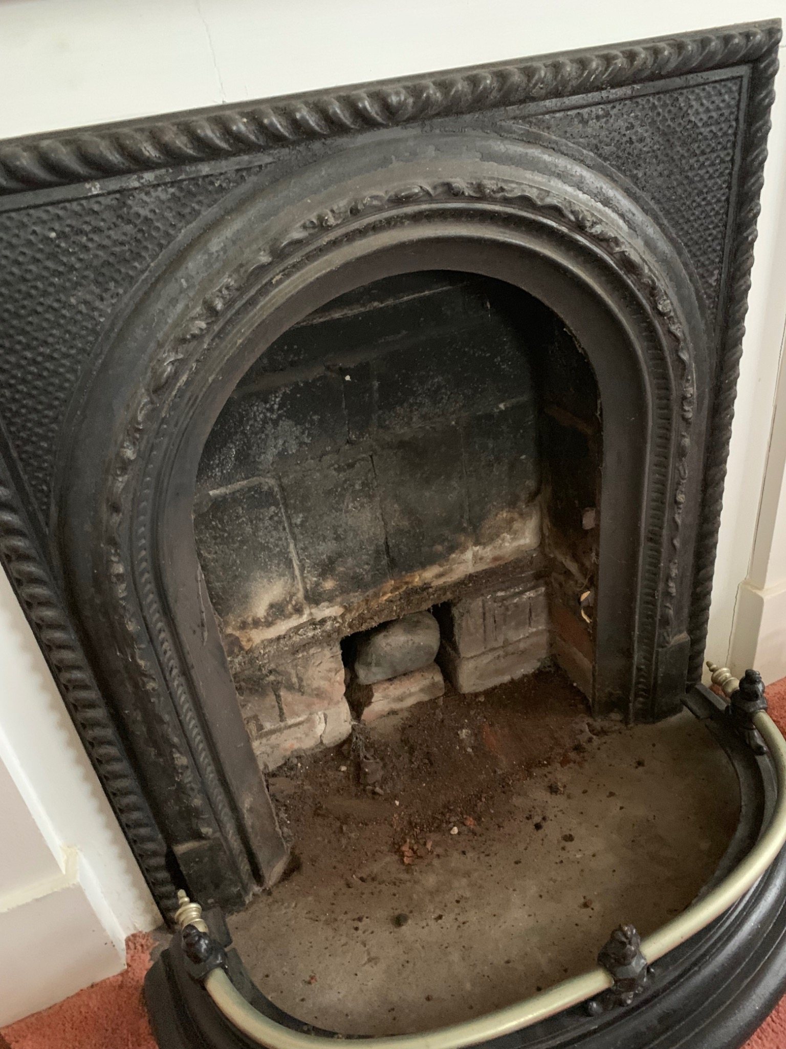 Older fireplace with cast iron surround and visible firebox interior