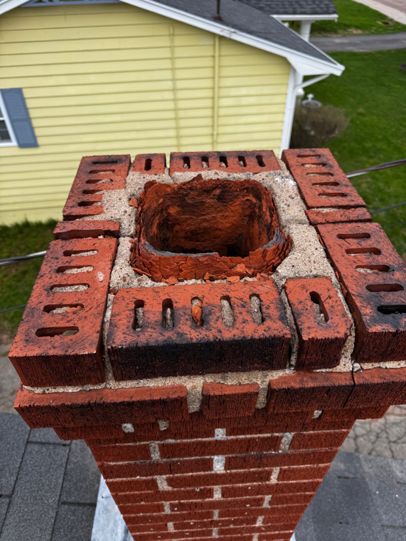 Deteriorated chimney top and flue termination exposed to PEI winter weather