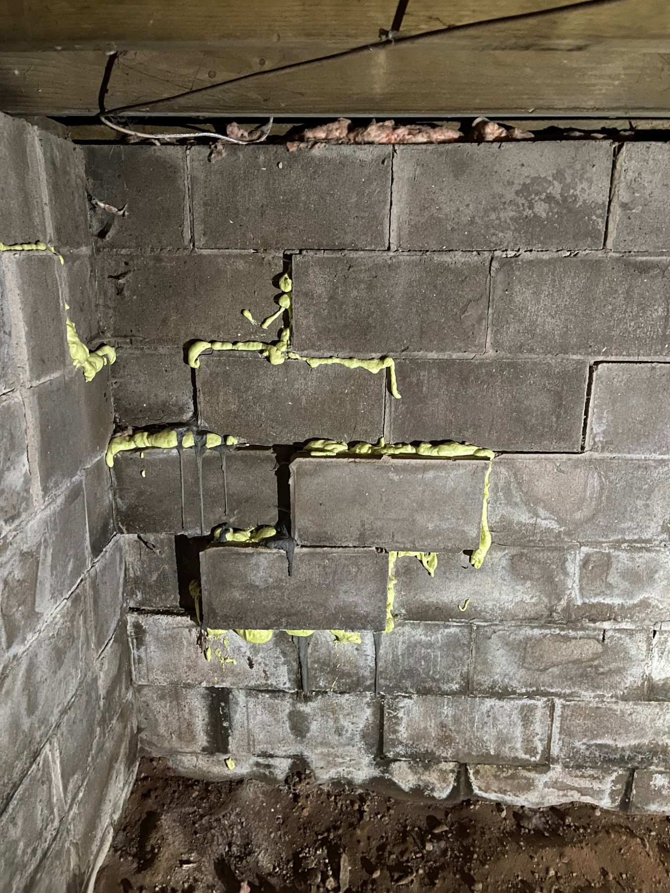 Displaced concrete masonry units and improvised foam-filled joints in a foundation wall