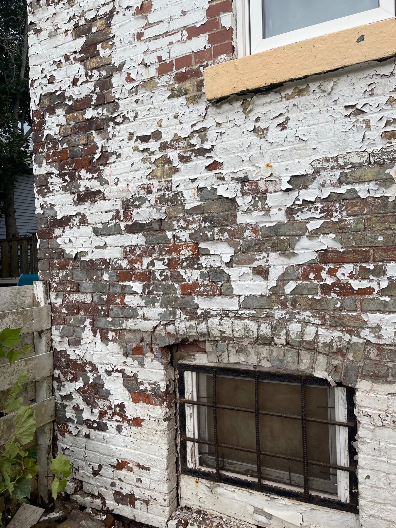 Peeling paint and coating failure on an older brick masonry wall