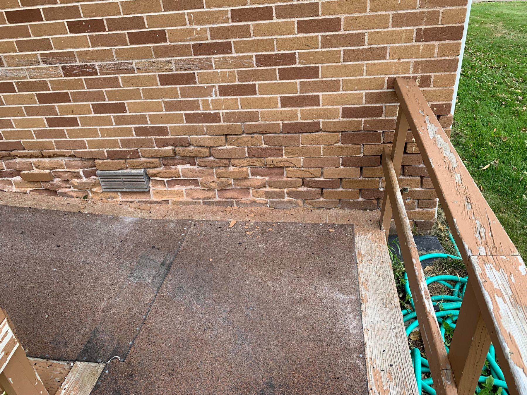 Severe brick face deterioration and spalling concentrated near the base of a PEI masonry wall