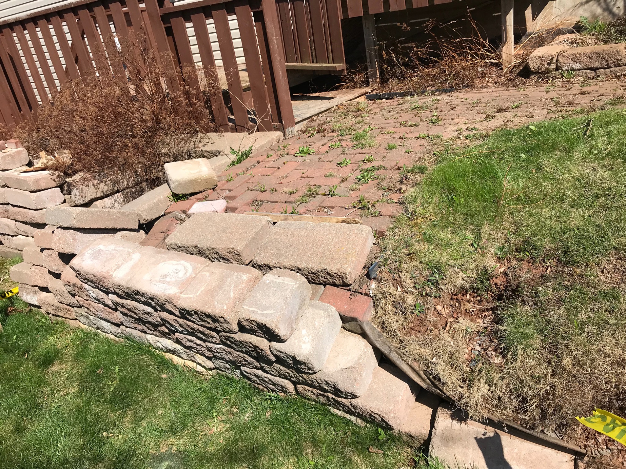 Small retaining wall beside a driveway showing displacement and failure near the corner