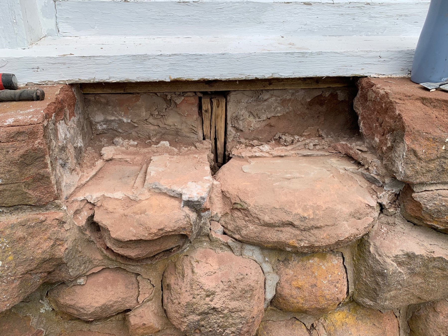 Opened stone masonry below a timber sill showing the transition between foundation masonry and framing