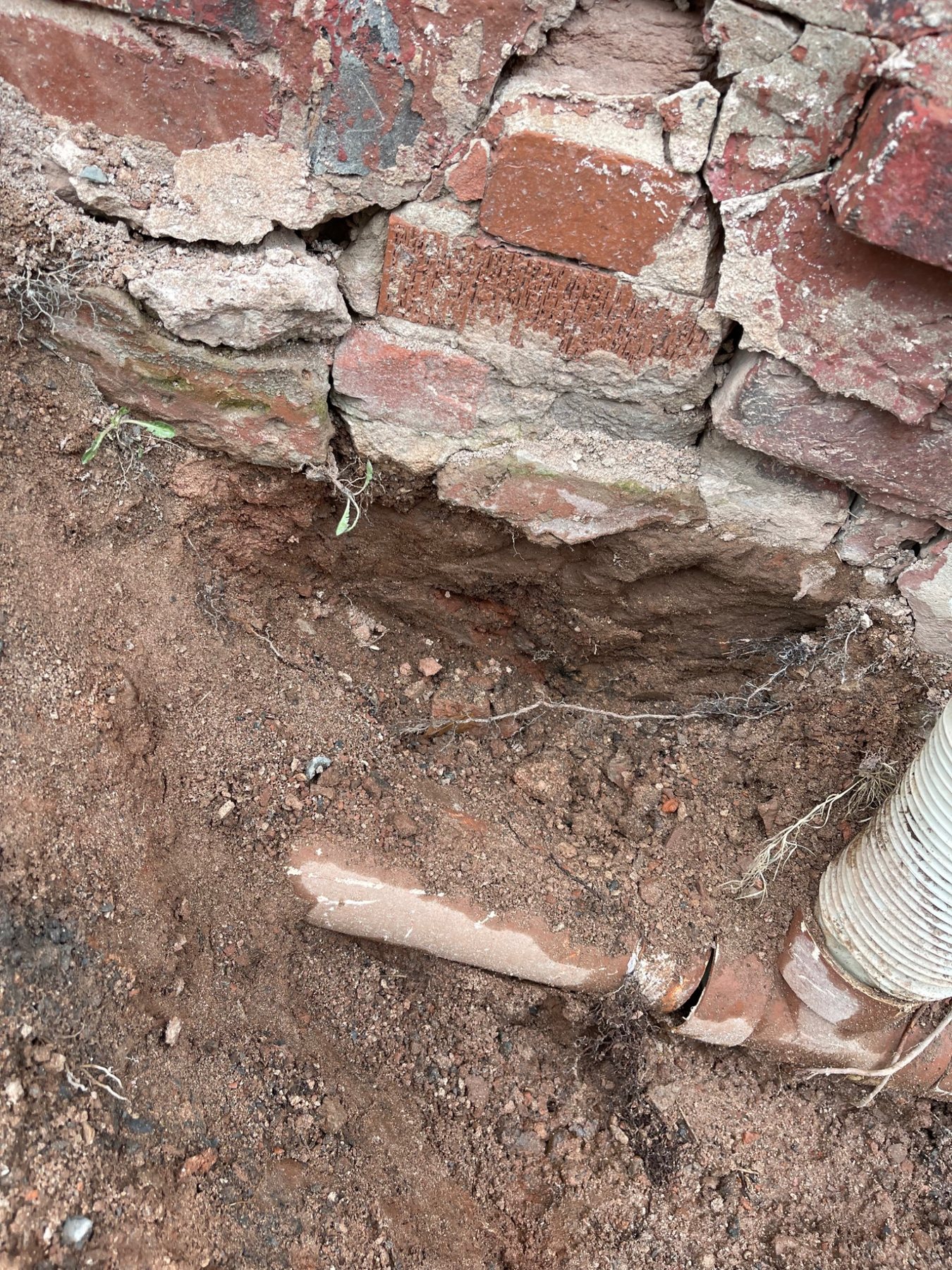 Excavated masonry foundation showing the lower wall, soil and exposed base condition
