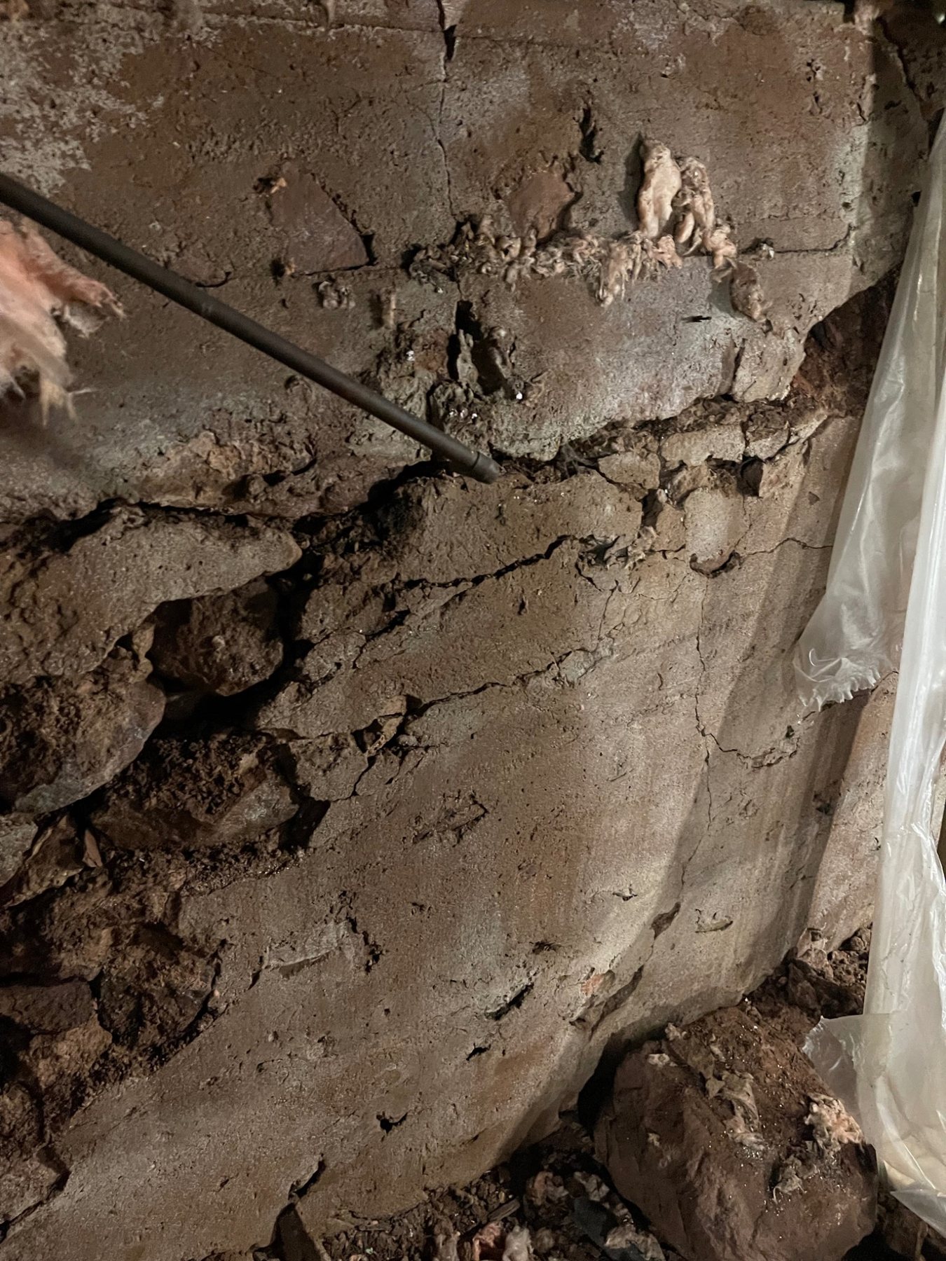 Old parging partially covering irregular stone masonry on the interior of a foundation wall