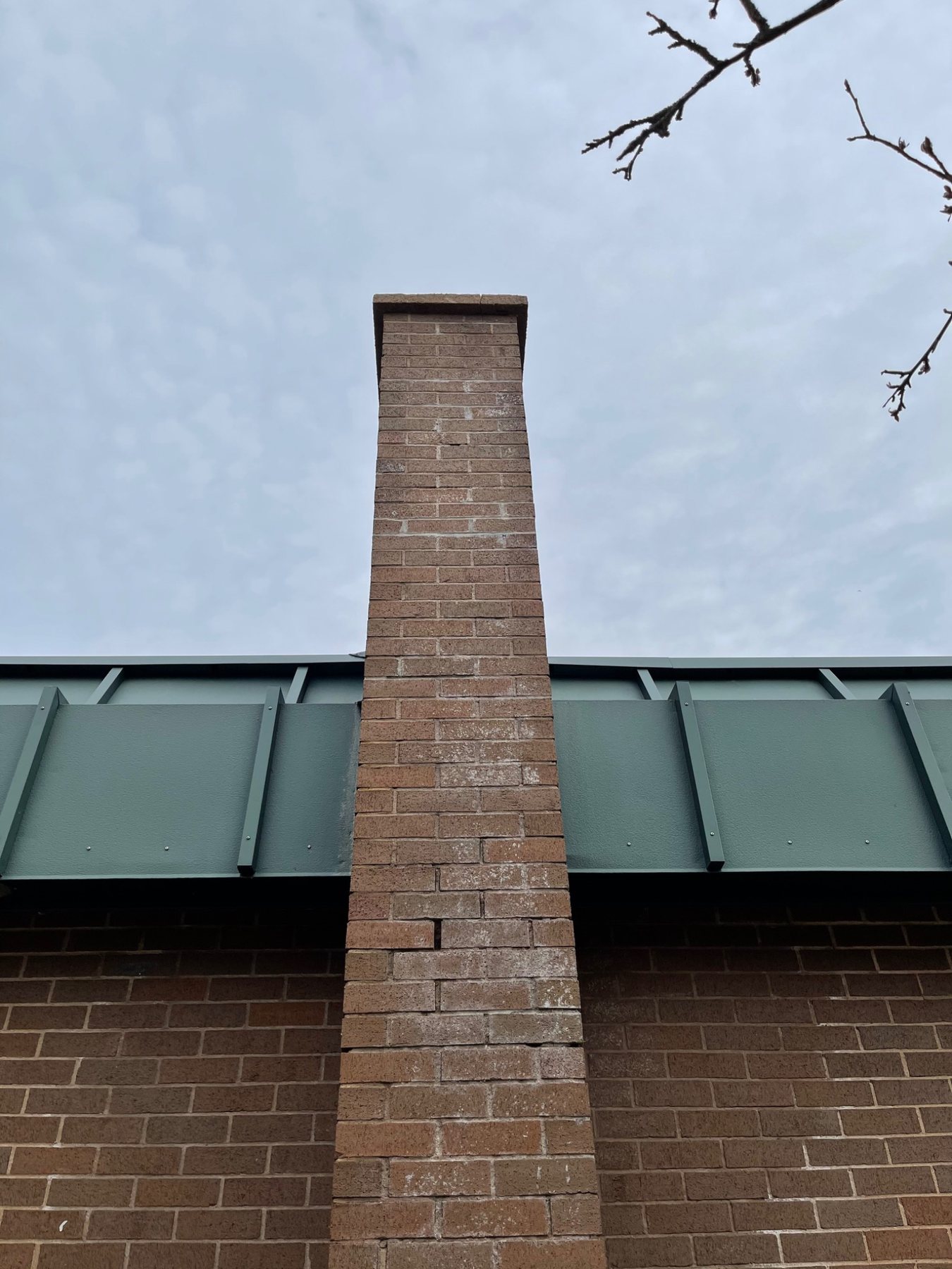 White efflorescence and weathered mortar visible on an exposed brick chimney in PEI