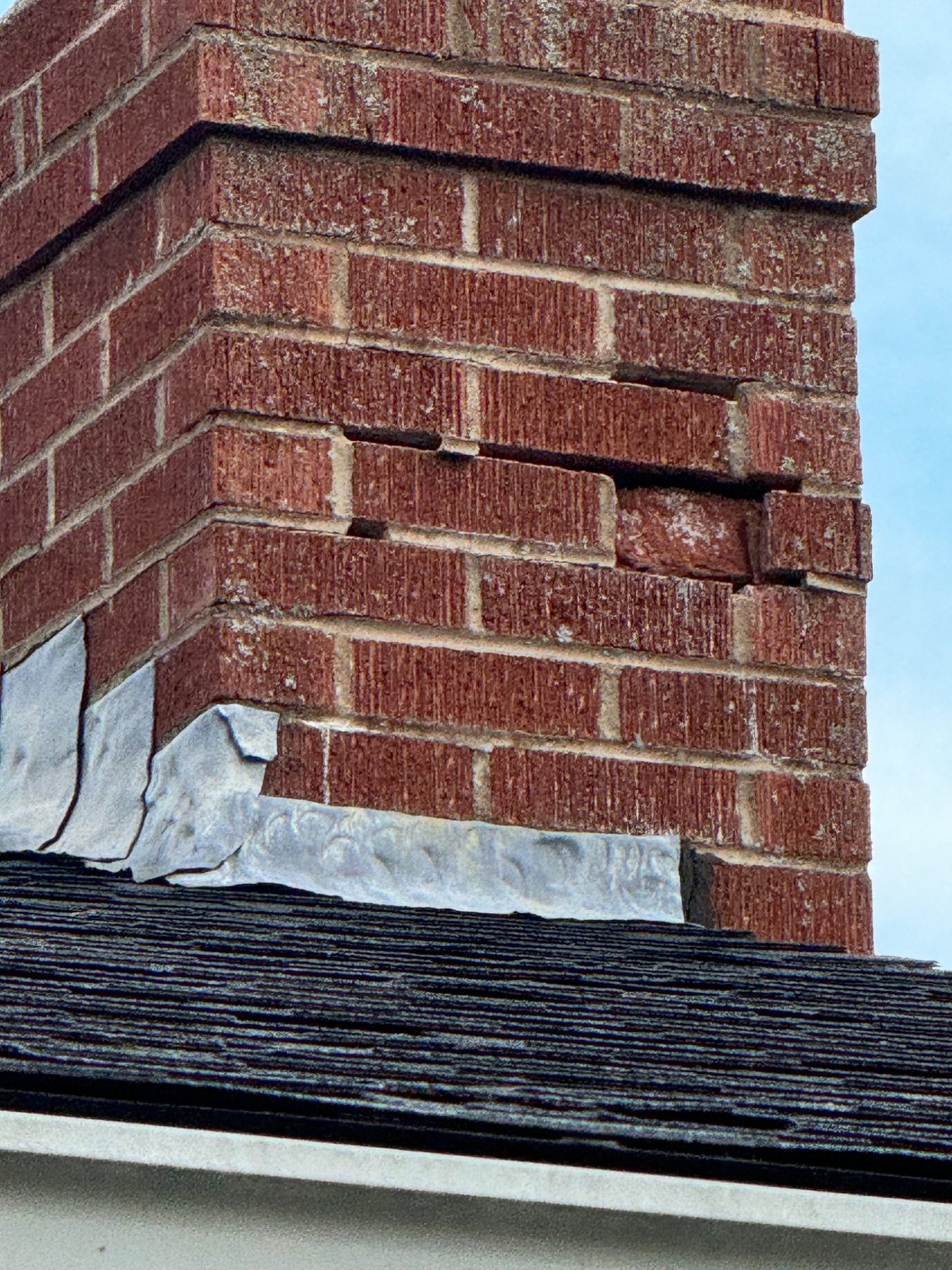 Loose and displaced brickwork on a chimney above a roof in Prince Edward Island