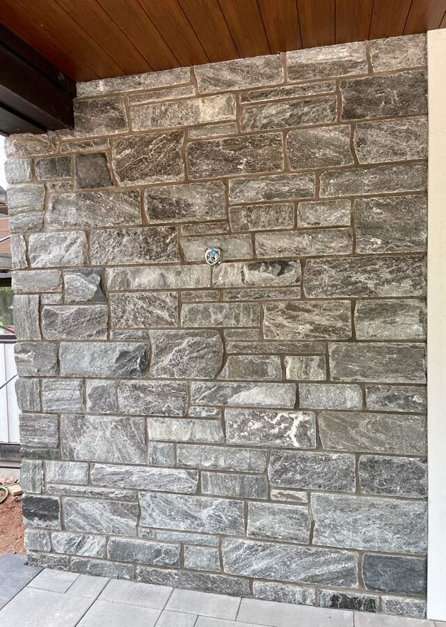 An image showing elite blue granite sawn height with linear coursing design and dark mortar joint